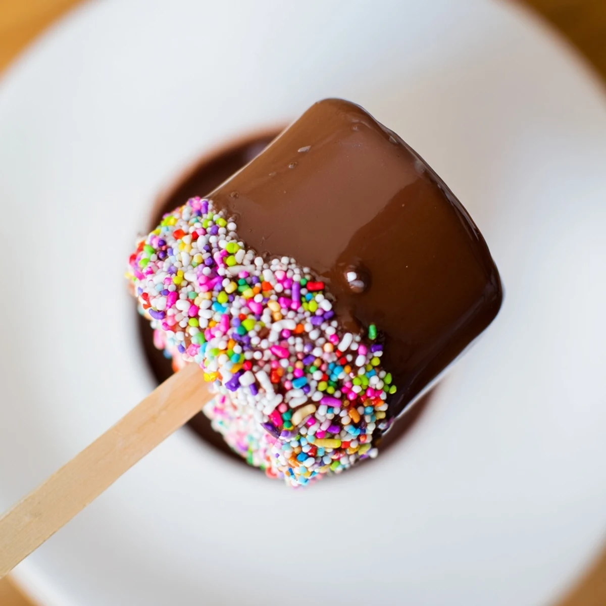 Tall, fluffy Chocolate Marshmallows on a Stick are fully dipped in glossy melted chocolate, finished with rainbow sprinkles for a festive party treat.