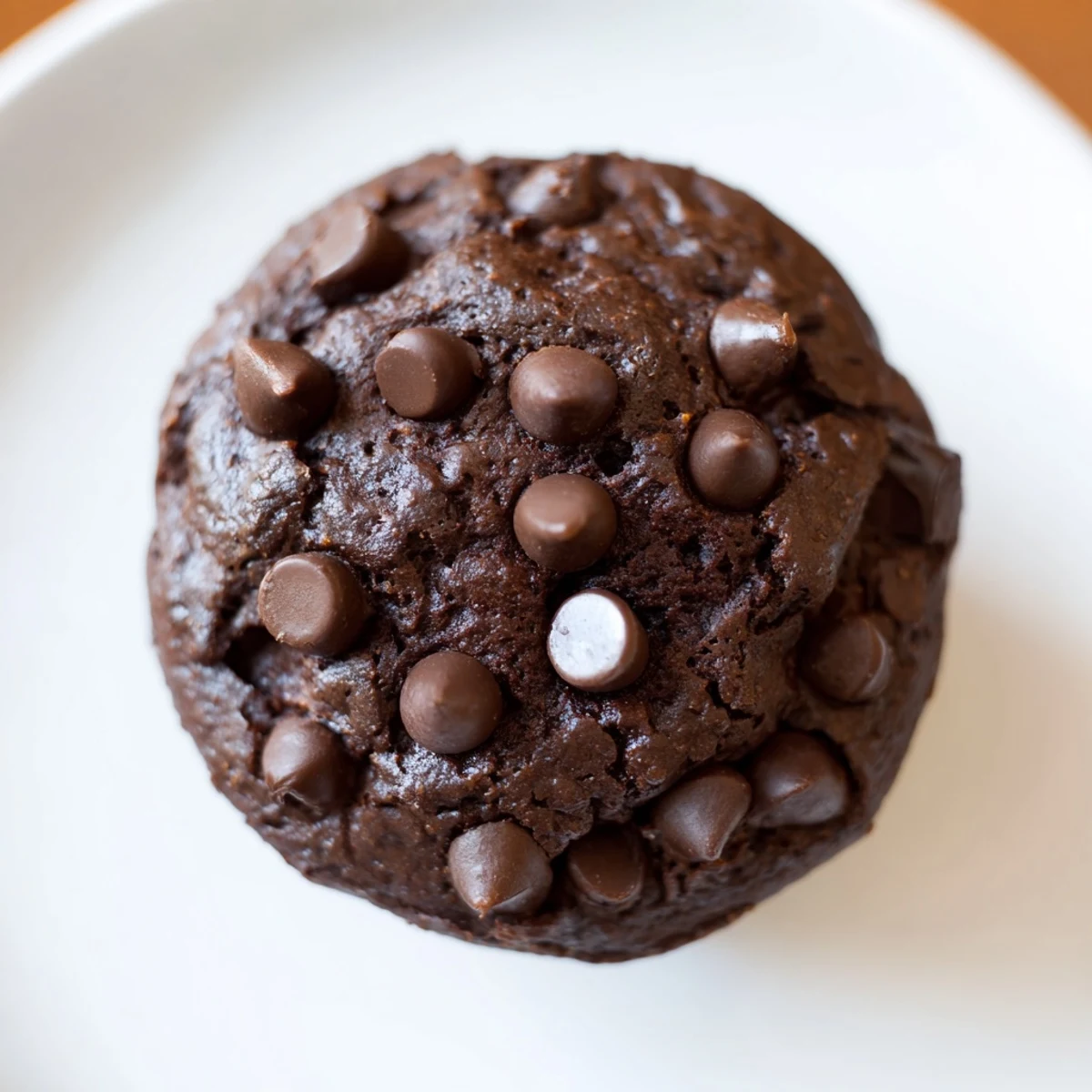 Freshly baked Chocolate Muffin Tops with chips sit on a cooling rack, boasting slightly crispy edges and soft, gooey centers.