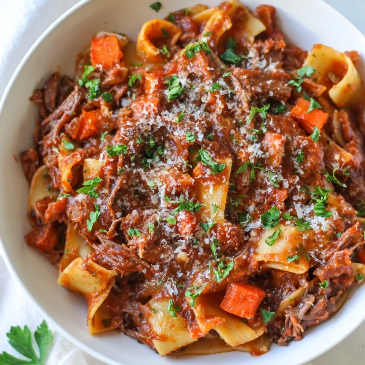 Close-up of tender shredded beef in Slow Cooker Beef Ragu, simmered in rich tomato sauce with herbs.