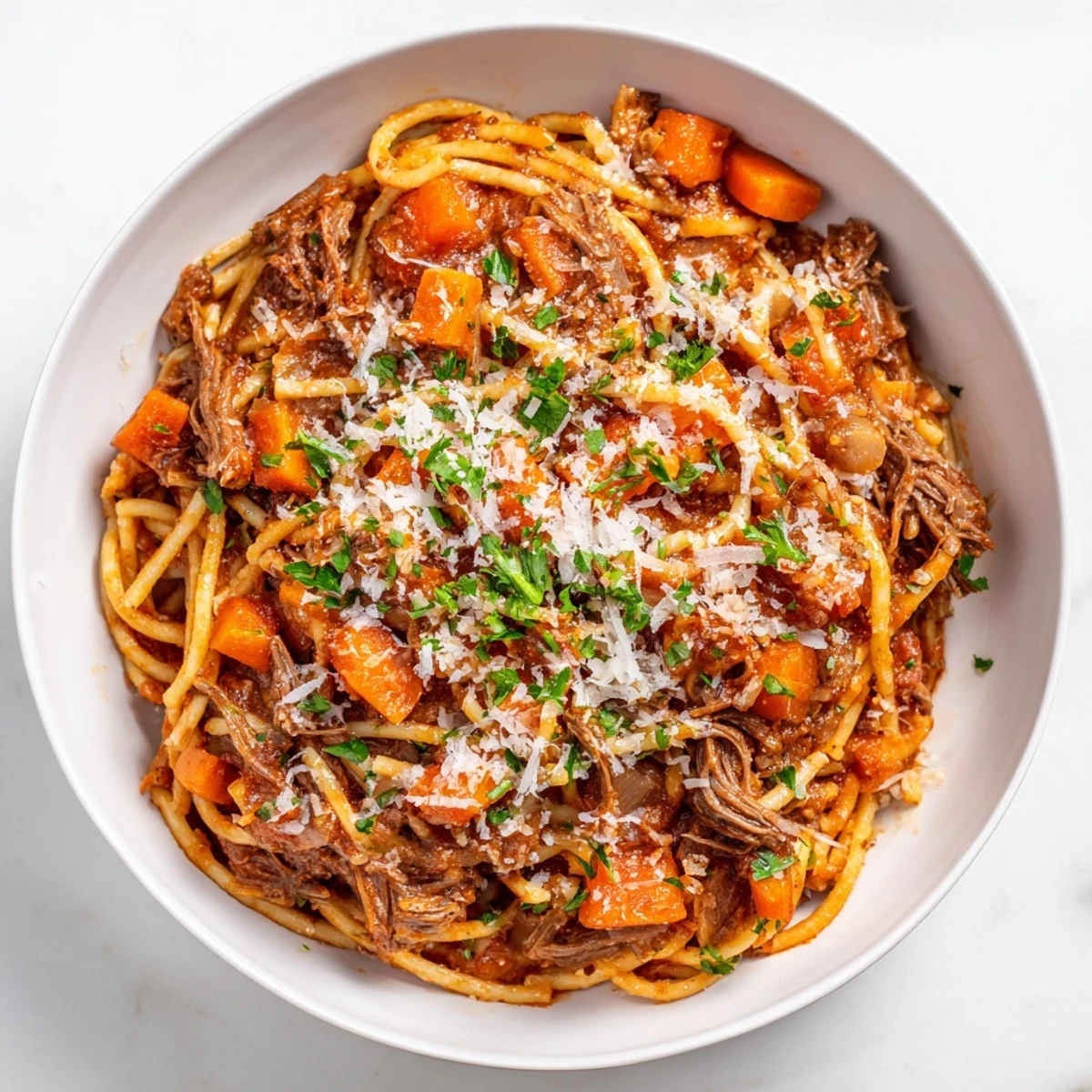 Garnished Slow Cooker Beef Ragu over spaghetti with melted Parmesan, ready for a comforting family dinner.