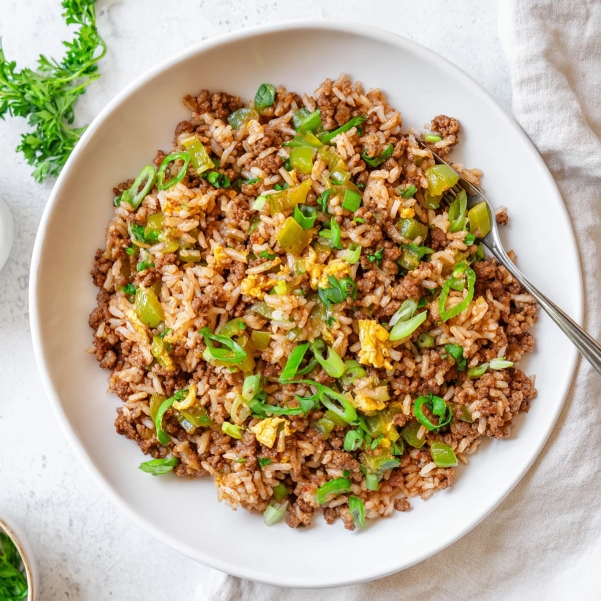 A hearty serving of Mardi Gras Dirty Rice with Beef, garnished with fresh parsley and spring onions, perfect for festive gatherings.