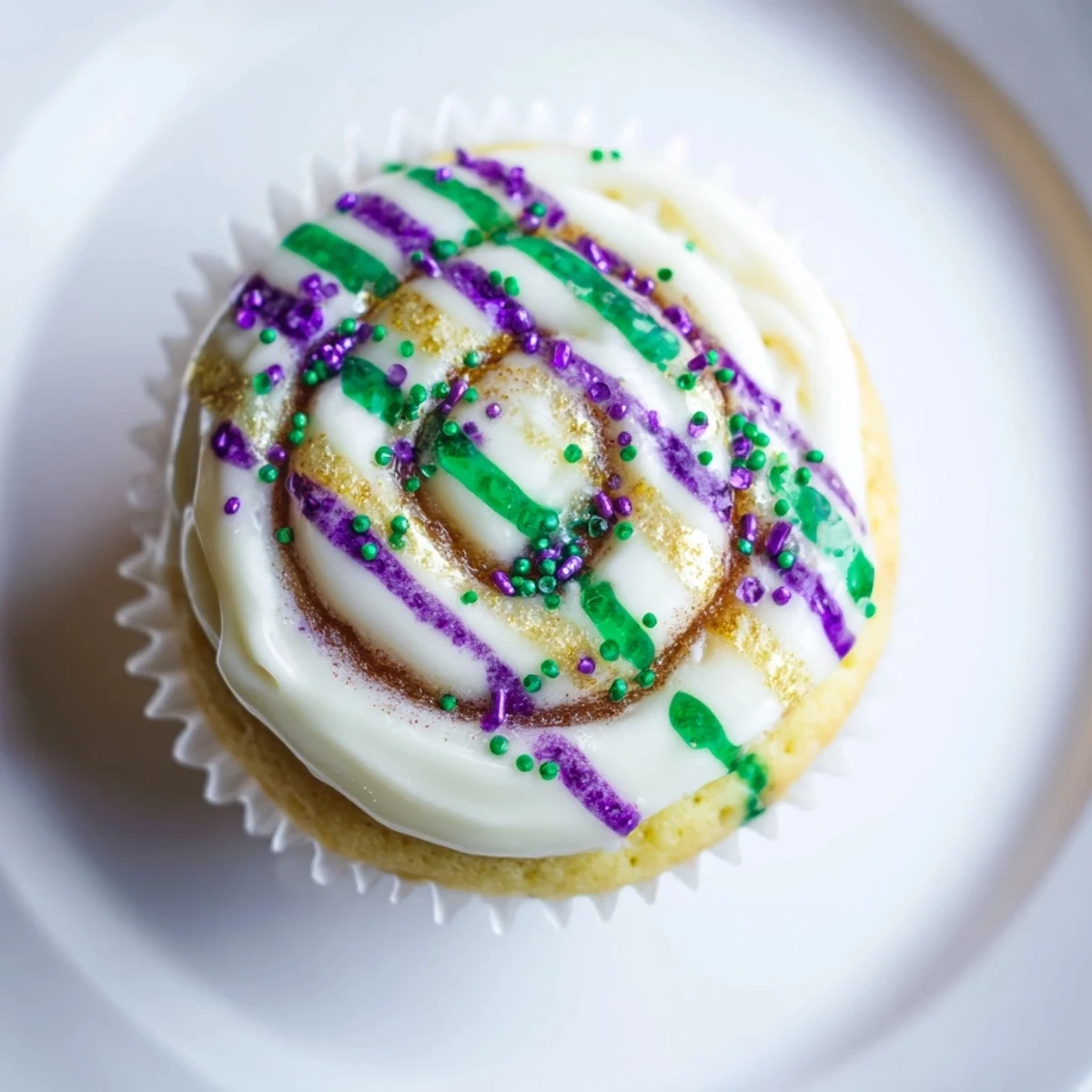 Cupcake with creamy icing, purple, green, and gold sugars, inspired by Mardi Gras King Cake Cupcakes.