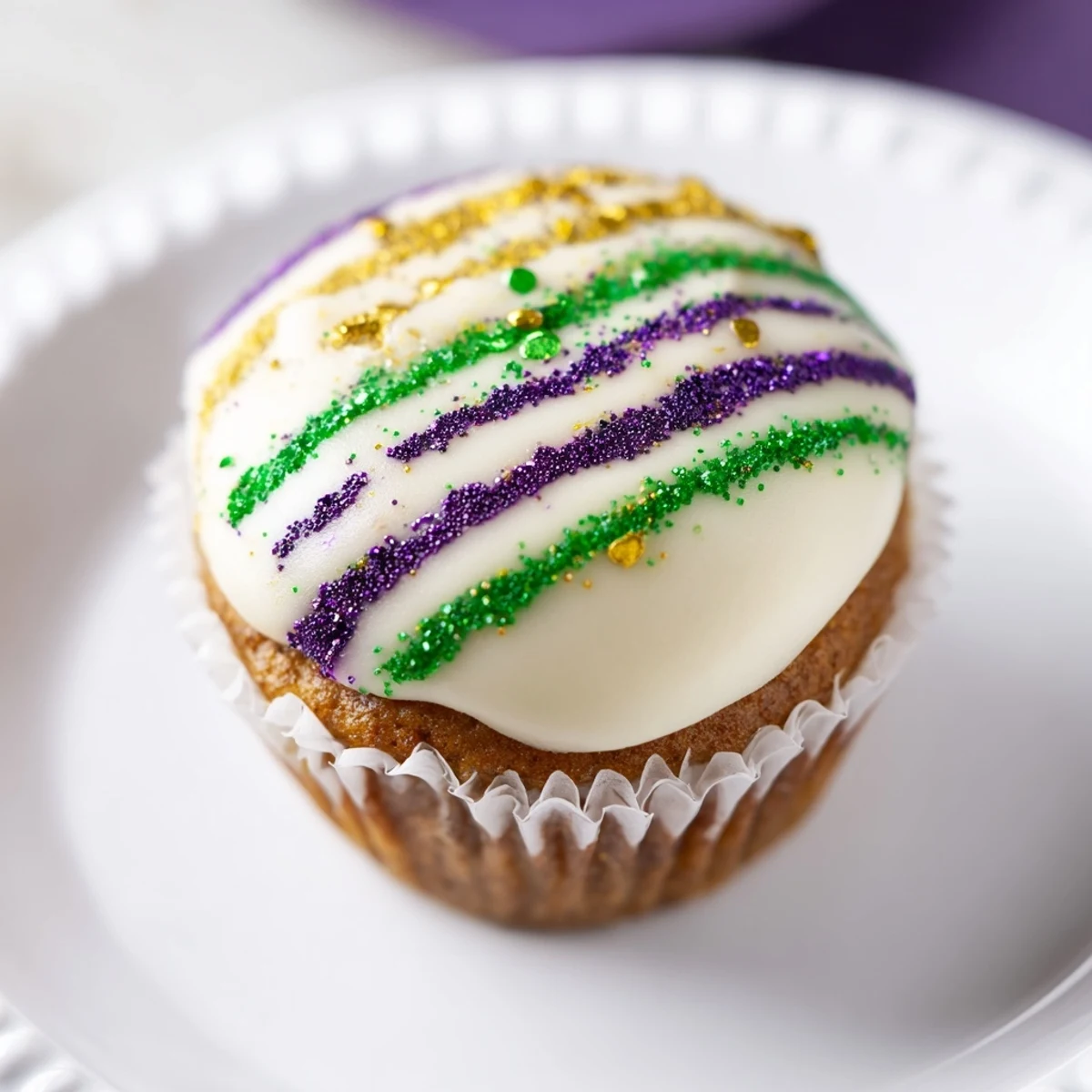 Mardi Gras King Cake Cupcakes, vanilla-cinnamon swirls, icing drizzle, and colorful sugar on a festive plate.