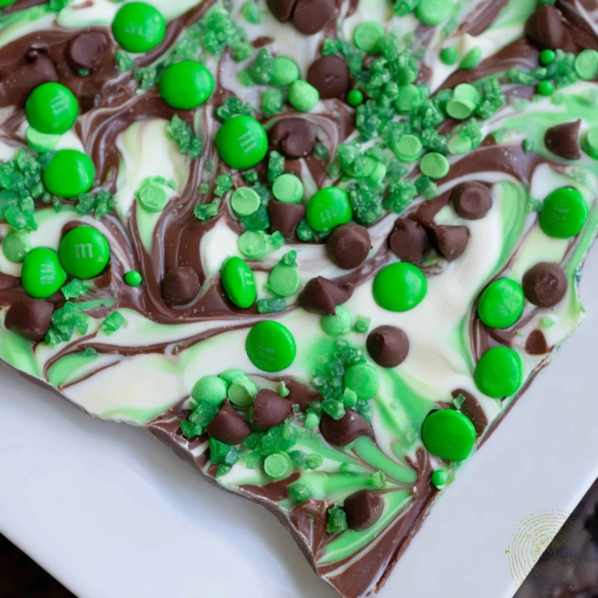 A festive St. Patricks Day Mint Chocolate Bark with marbled white and dark chocolate, studded with mint candies and mini chips.