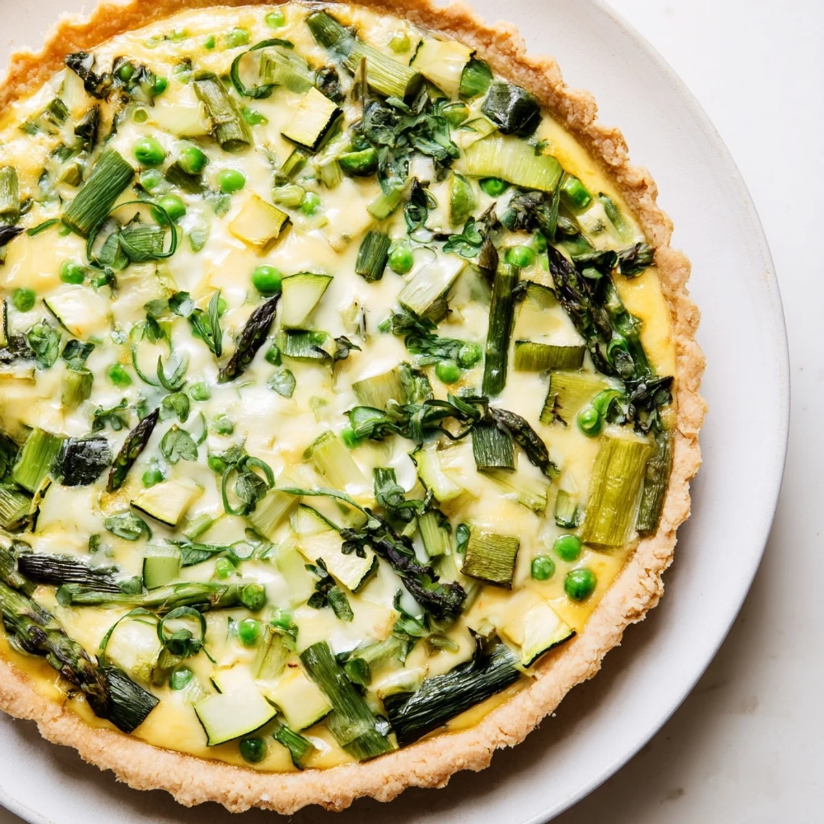 Fresh Spring Vegetable Quiche with buttery crust and golden custard, filled with asparagus, zucchini, and peas.  