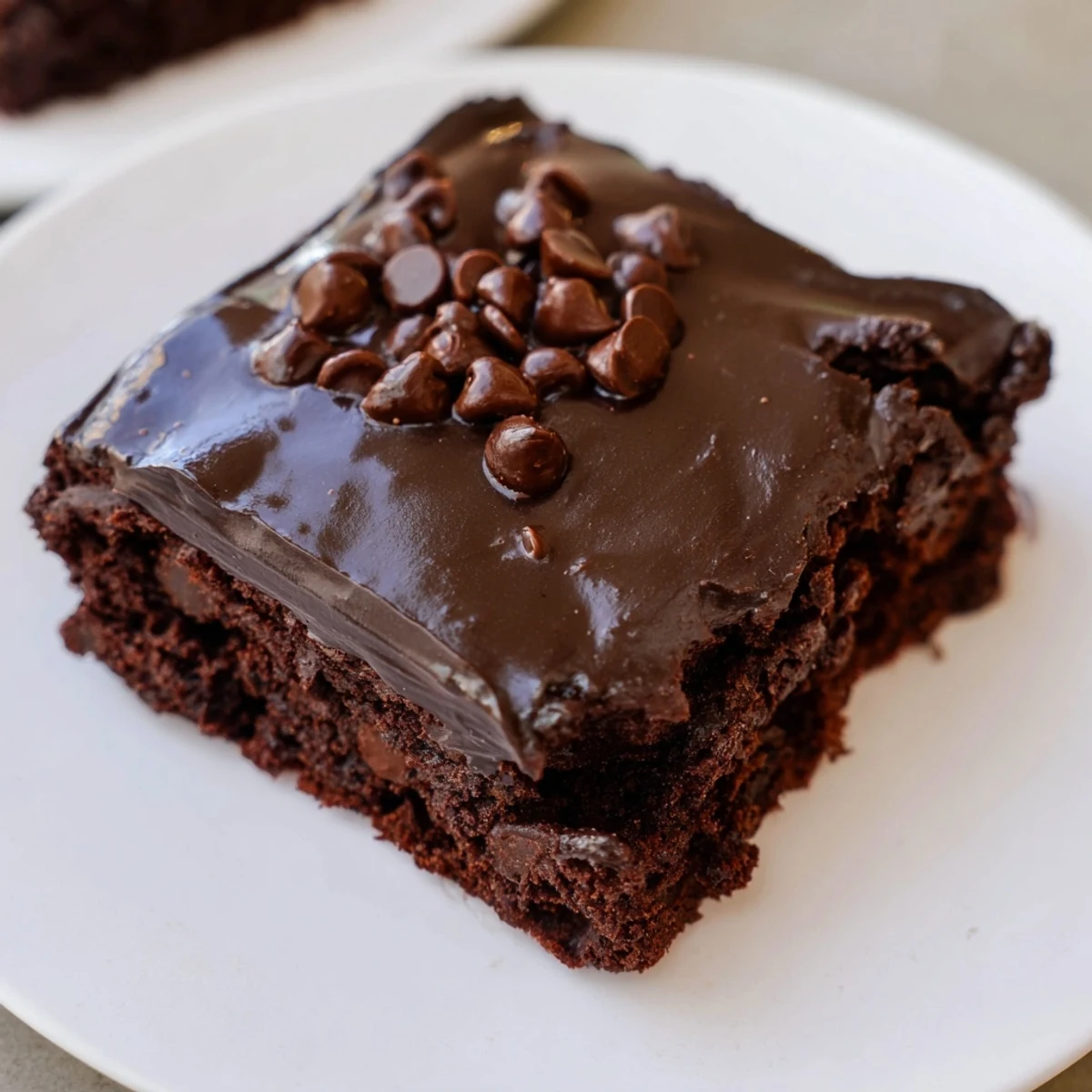 Rich, fudgy Mint Chocolate Chip Brownies with Ganache topped with glossy dark chocolate and fresh mint garnish.