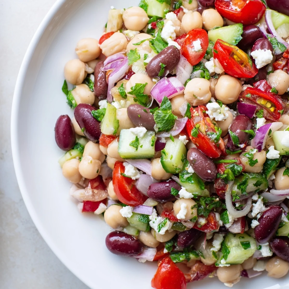 Serving suggestion of Mediterranean Dense Bean Salad beside grilled chicken, showing vibrant beans and vegetables tossed in olive oil for a protein-rich lunch.