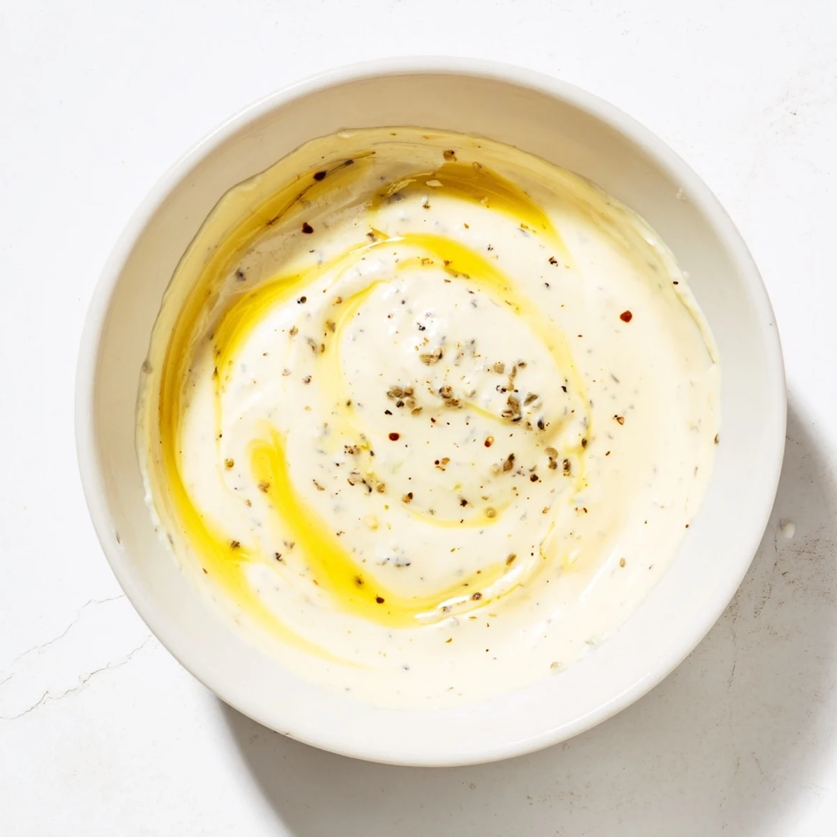 A fresh lemon Dijon dressing recipe in a white bowl, garnished with herbs and ready to toss with greens.
