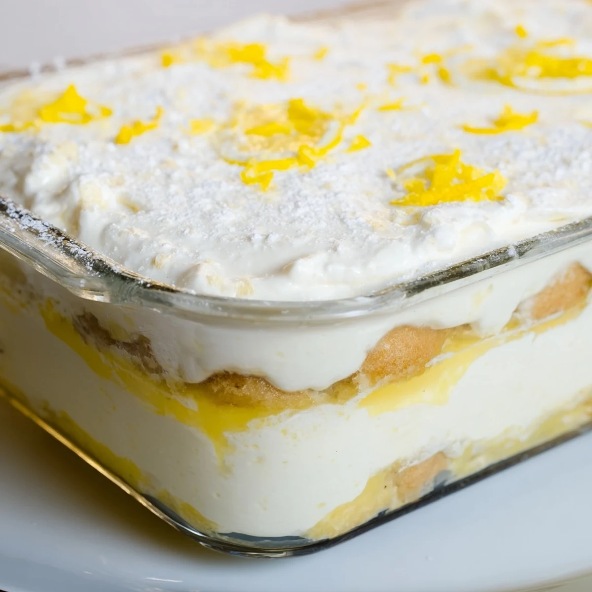 The finished Easy Lemon Tiramisu No Bake Dessert topped with fresh lemon slices and a dusting of powdered sugar.