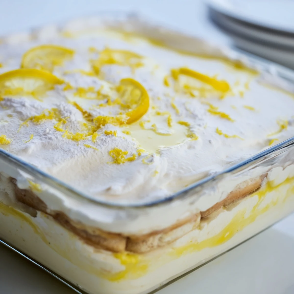 A slice of Easy Lemon Tiramisu No Bake Dessert layered with creamy mascarpone and bright zest on a white plate.