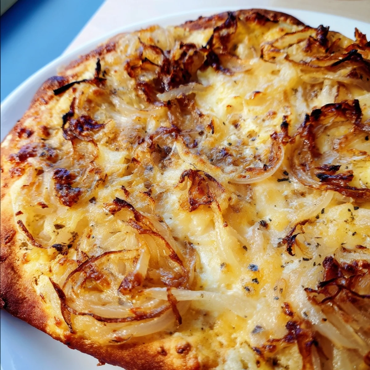 A close-up of a freshly baked Caramelized Onion Pizza With Melty Cheese on a wooden board, showcasing golden crust and bubbling cheese.