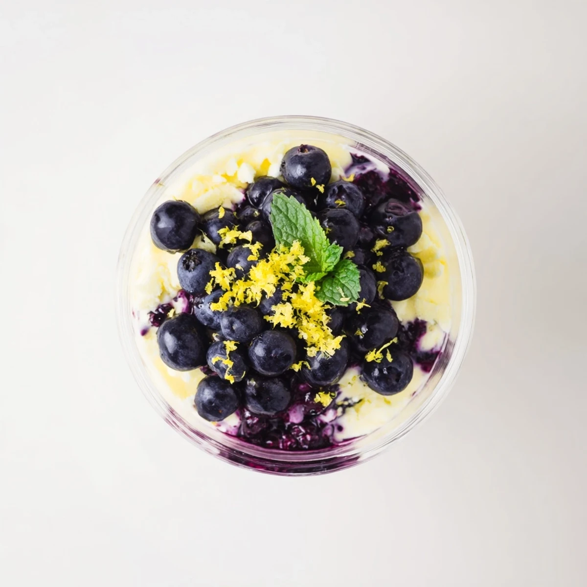 A close-up of Lemon Blueberry Mousse showing its airy texture and glossy blueberry topping on a rustic kitchen table.