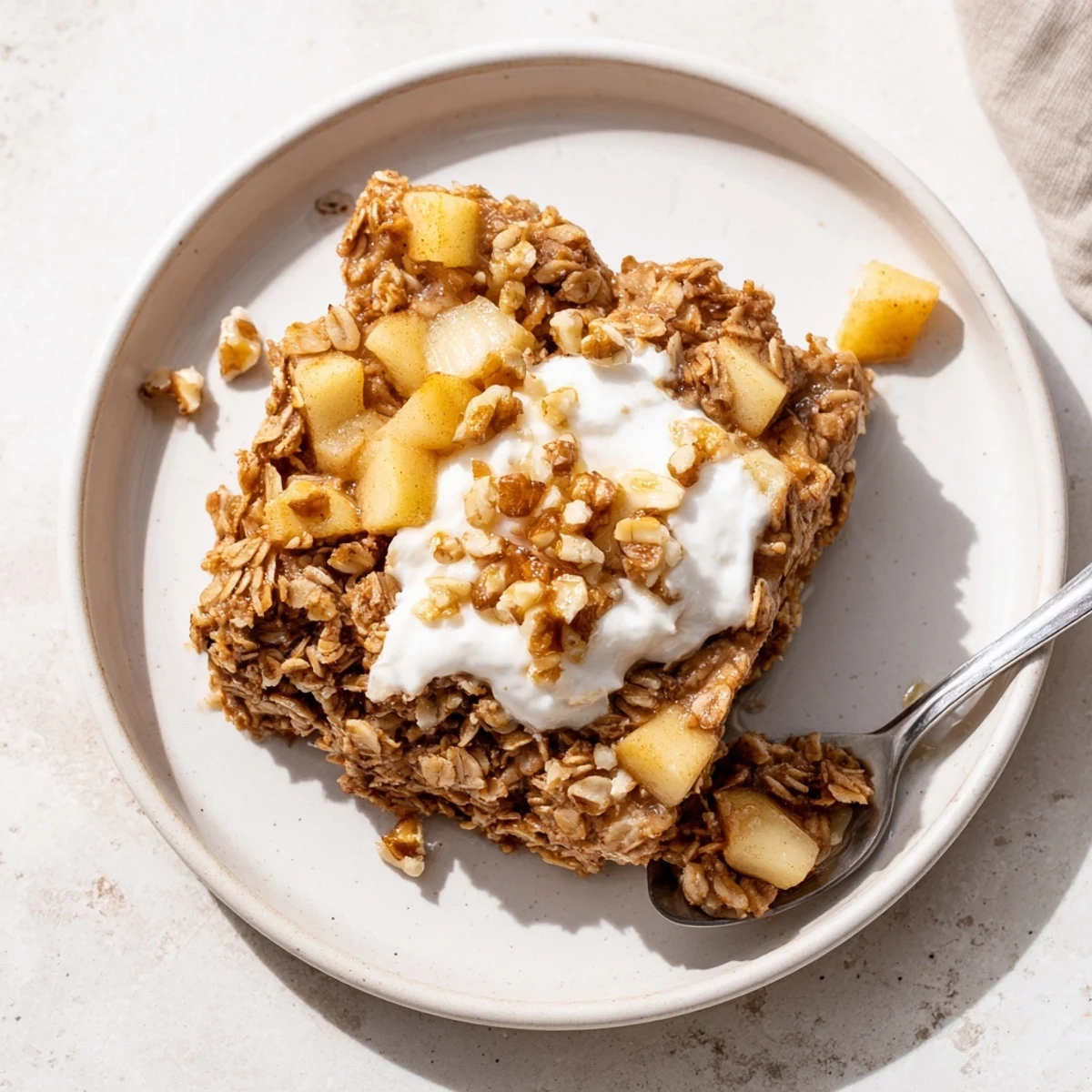 A close-up of baked apple oatmeal with Greek yogurt showing moist oats and tender apple pieces.