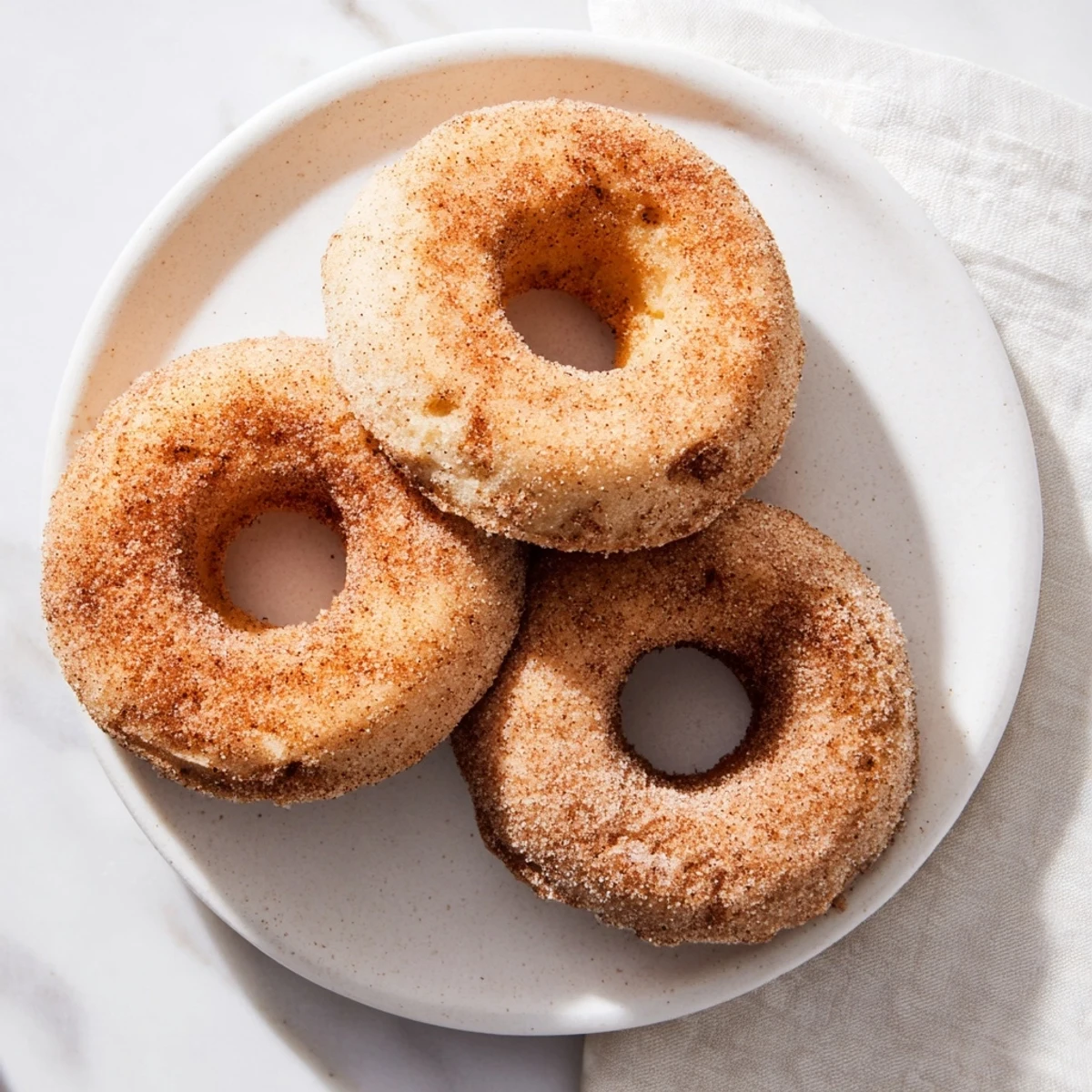 A close-up of Delicious Baked Cinnamon Sugar Donuts you can’t resist, showing a fluffy texture and sparkling sugar coating on a cooling rack.