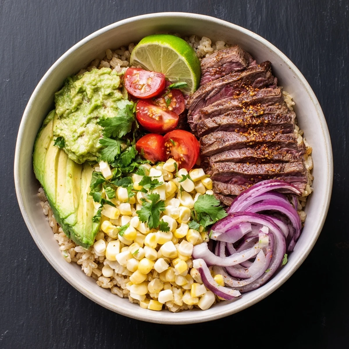 Juicy grilled steak and creamy avocado top this Steak Avocado Roasted Corn Bowl with lime dressing.