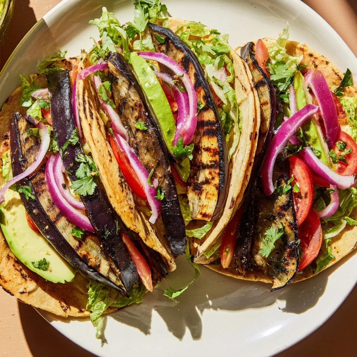 A close-up of Charred Eggplant Tacos showing charred eggplant slices and fresh cilantro garnish.