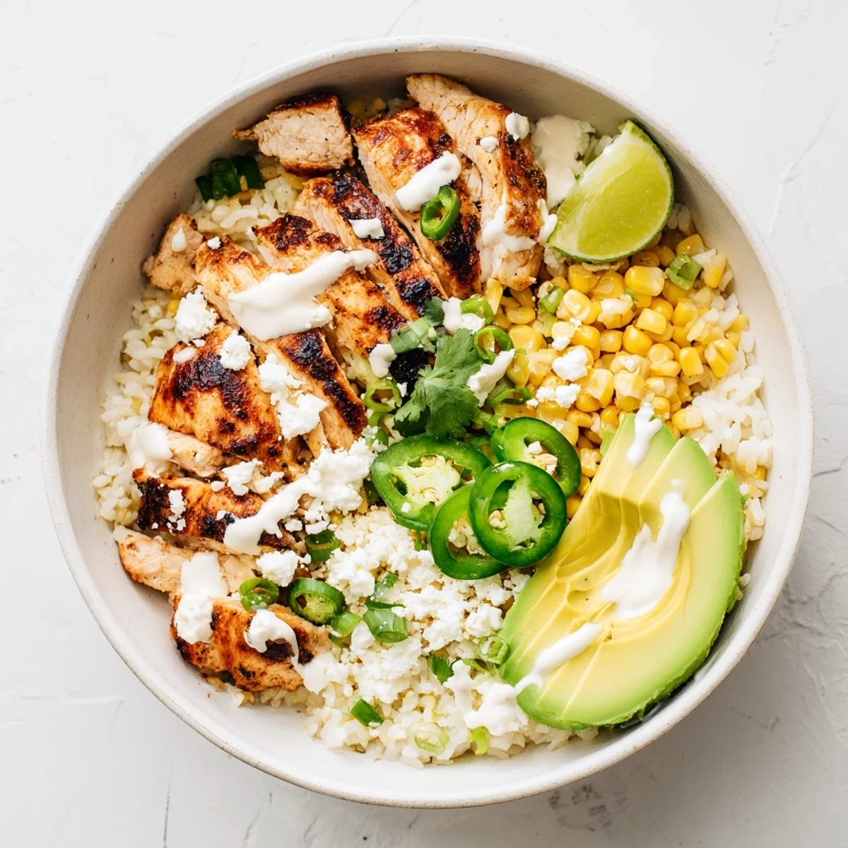 A close-up of the Street Corn Chicken Bowl with creamy avocado, cilantro, and jalapeños on fluffy rice ready to serve.