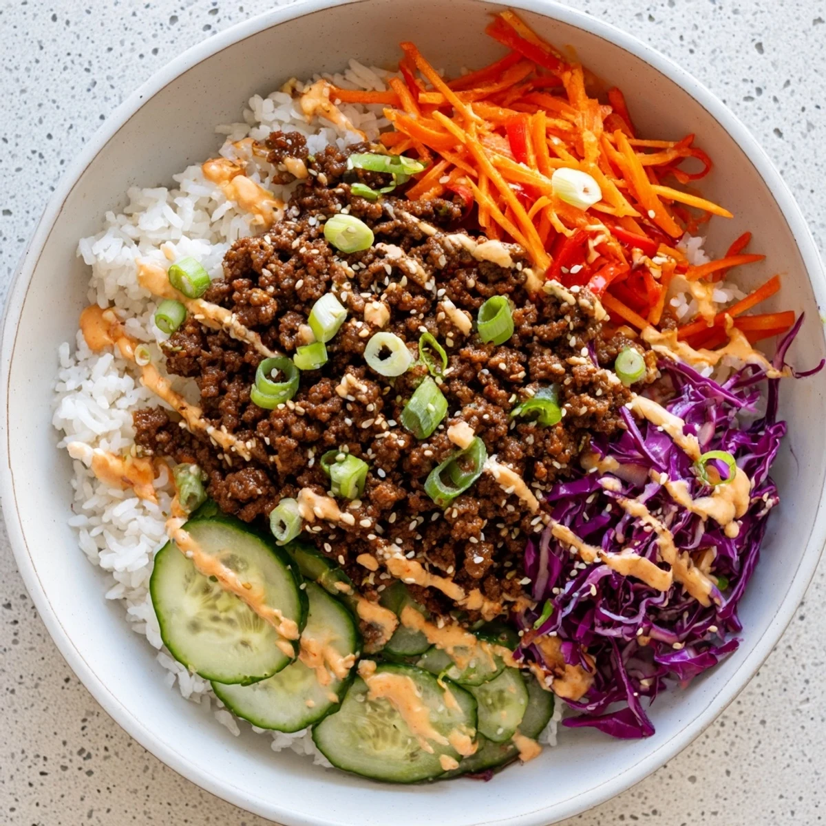 A close-up of a Korean Beef Bowl with Spicy Mayo, featuring tender ground beef, fluffy rice, and vibrant fresh veggies.