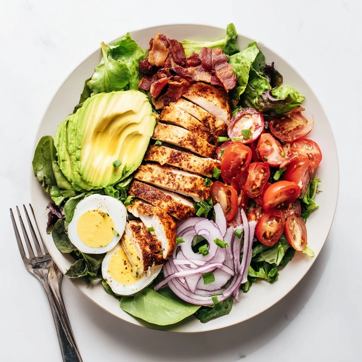 Freshly grilled chicken rests atop vibrant mixed greens with cherry tomatoes and avocado in this Paleo Grilled Chicken Cobb Salad With Honey Dijon Dressing, ready to serve.