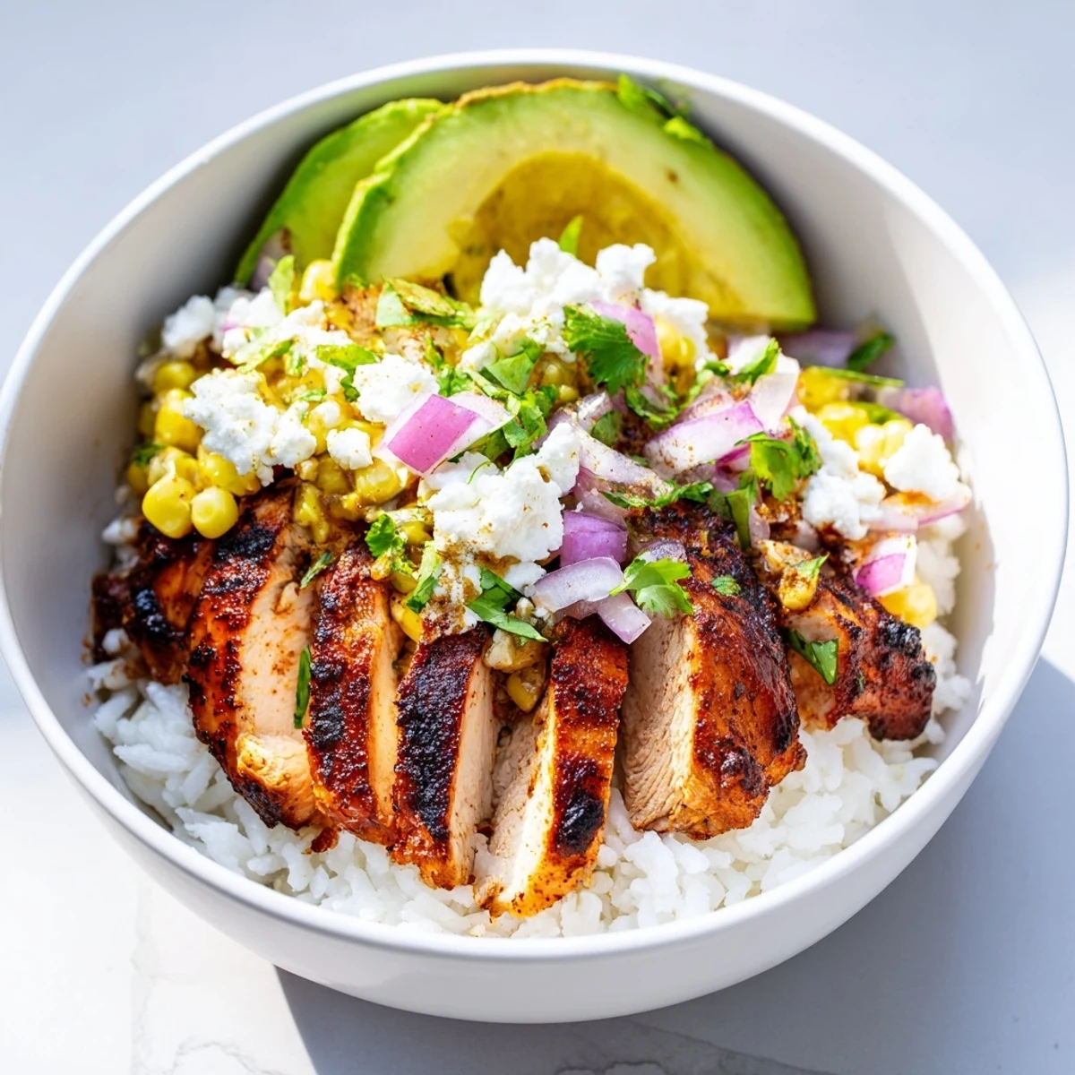 Vibrant street corn chicken rice bowl topped with charred corn, juicy chicken, and zesty lime
