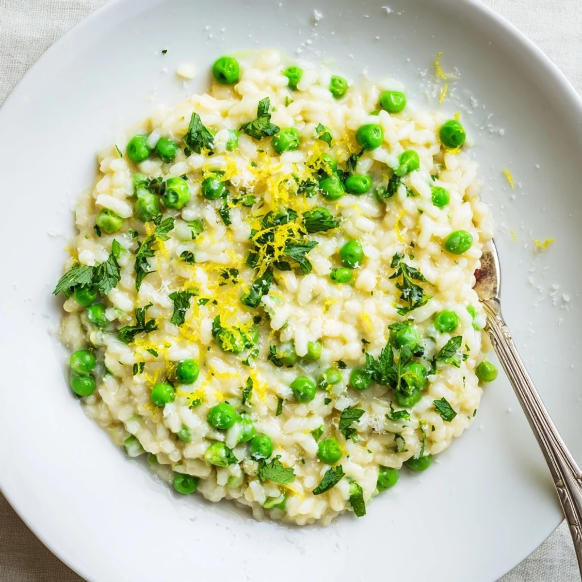 Creamy spring pea risotto topped with fresh grated Parmesan and bright green herbs