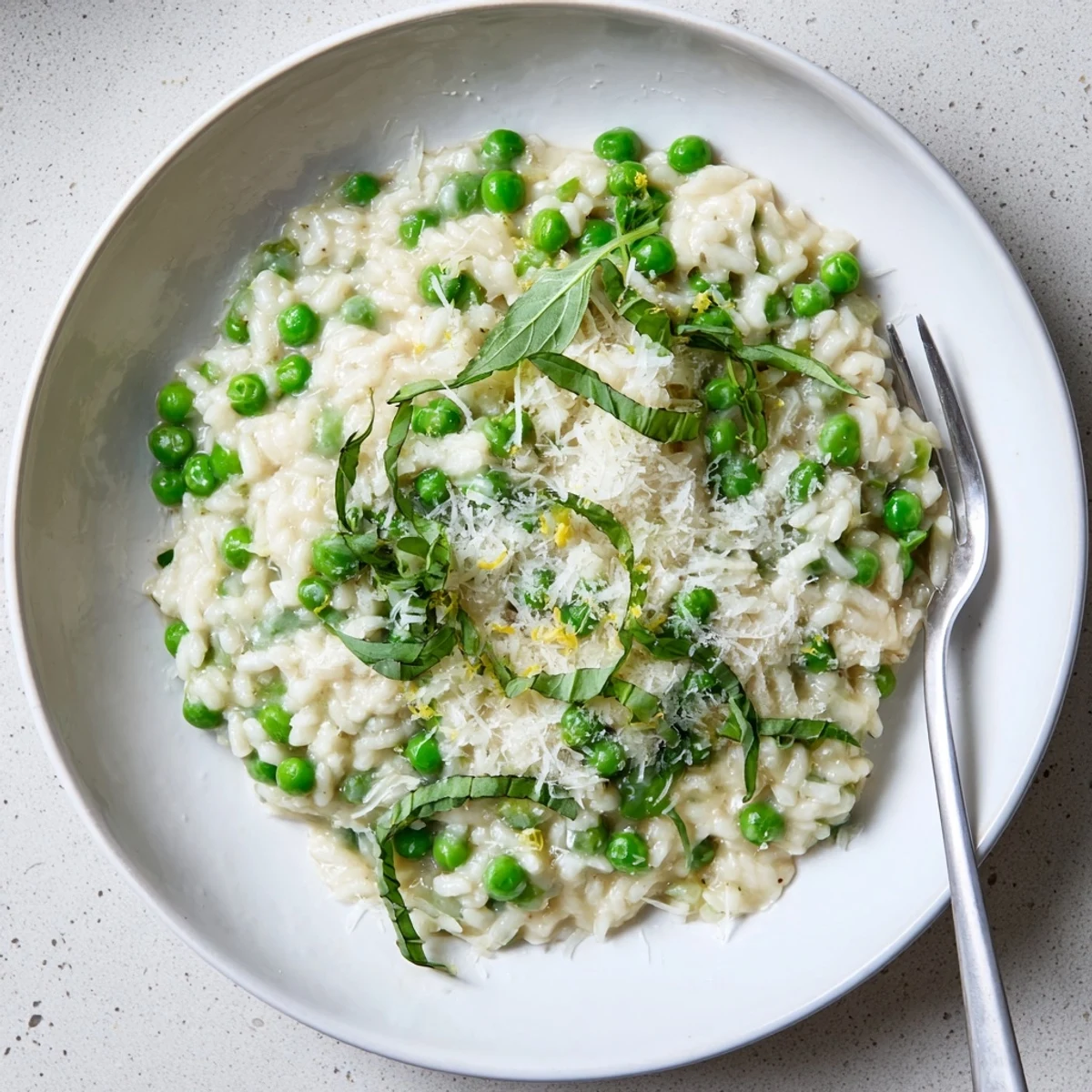 Creamy spring pea risotto topped with grated Parmesan and fresh green basil chiffonade