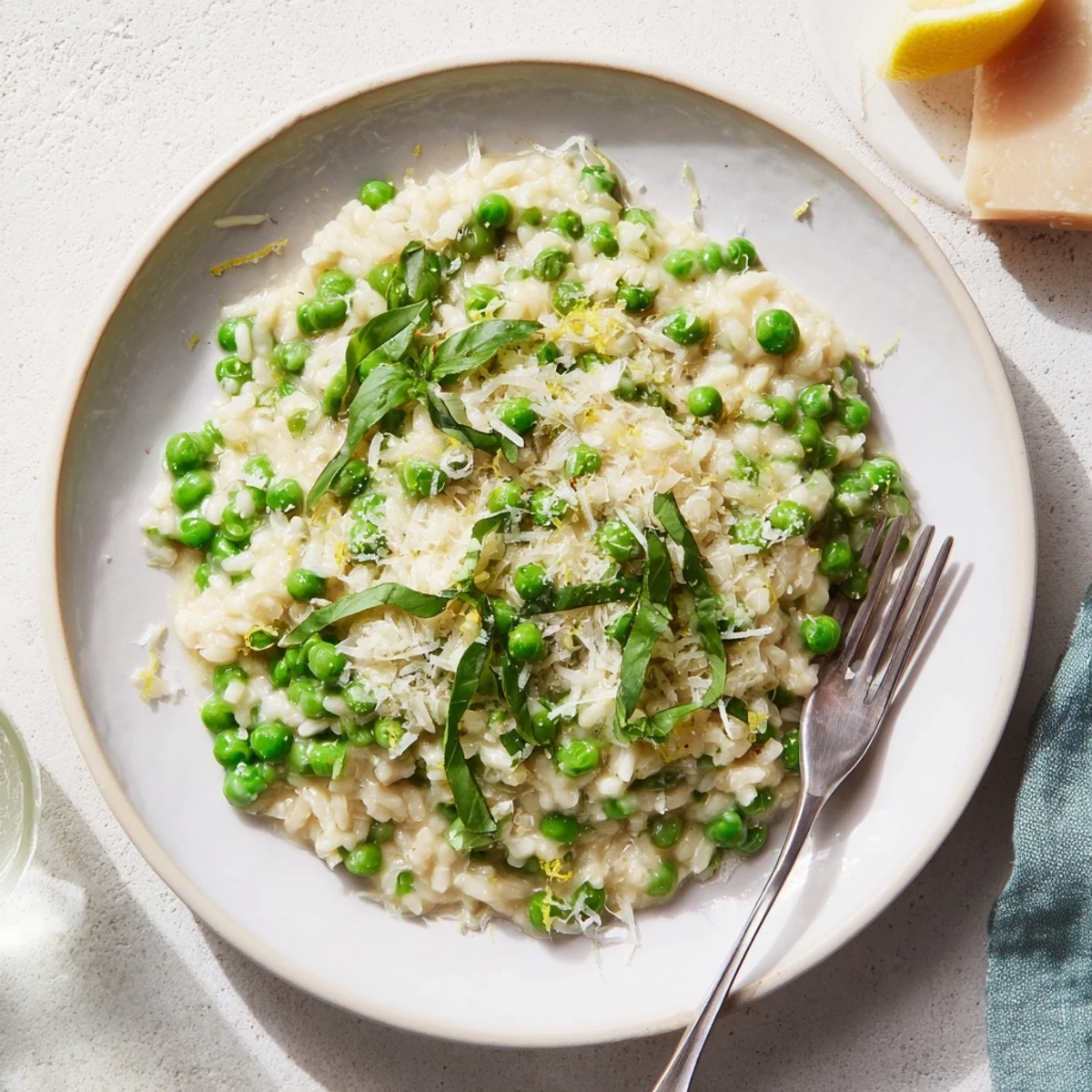 Golden plate of Italian spring pea risotto garnished with fresh basil and lemon zest