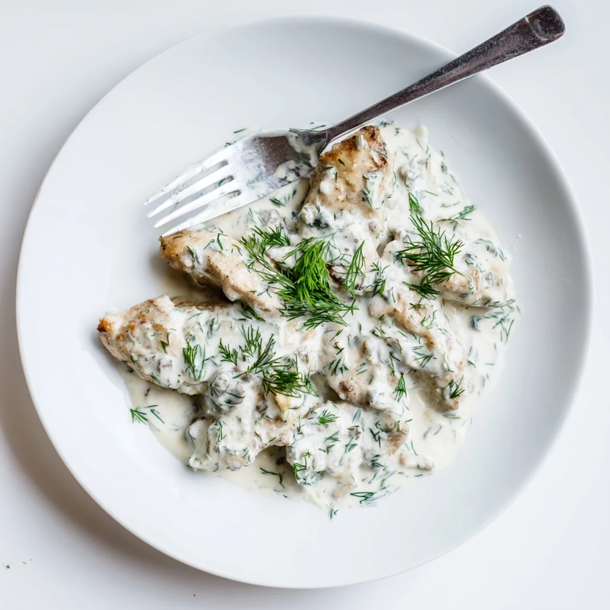 Golden brown chicken breasts swimming in a rich creamy dill sauce with fresh herbs