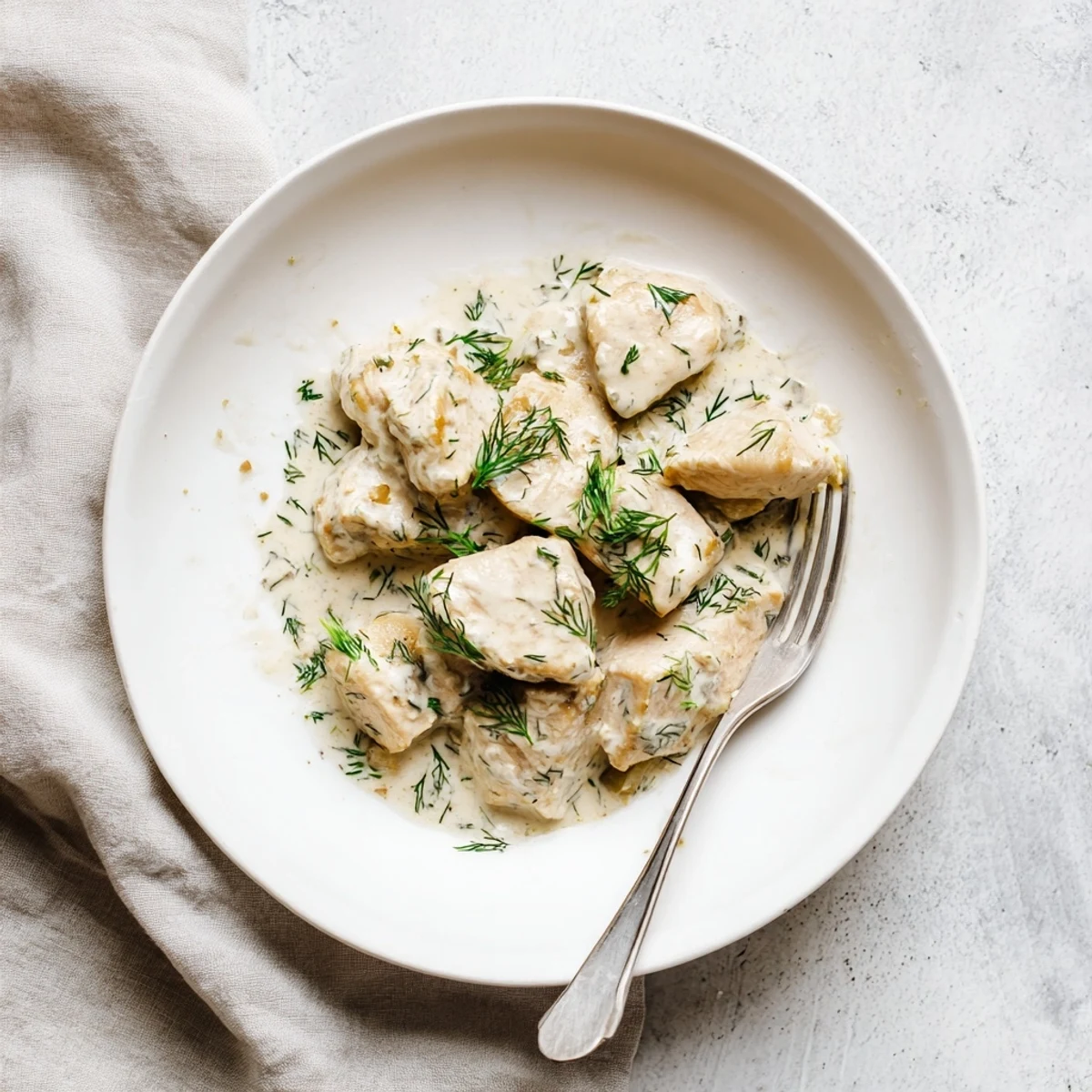 Savory creamy dill chicken plated with a generous white sauce and bright dill garnish
