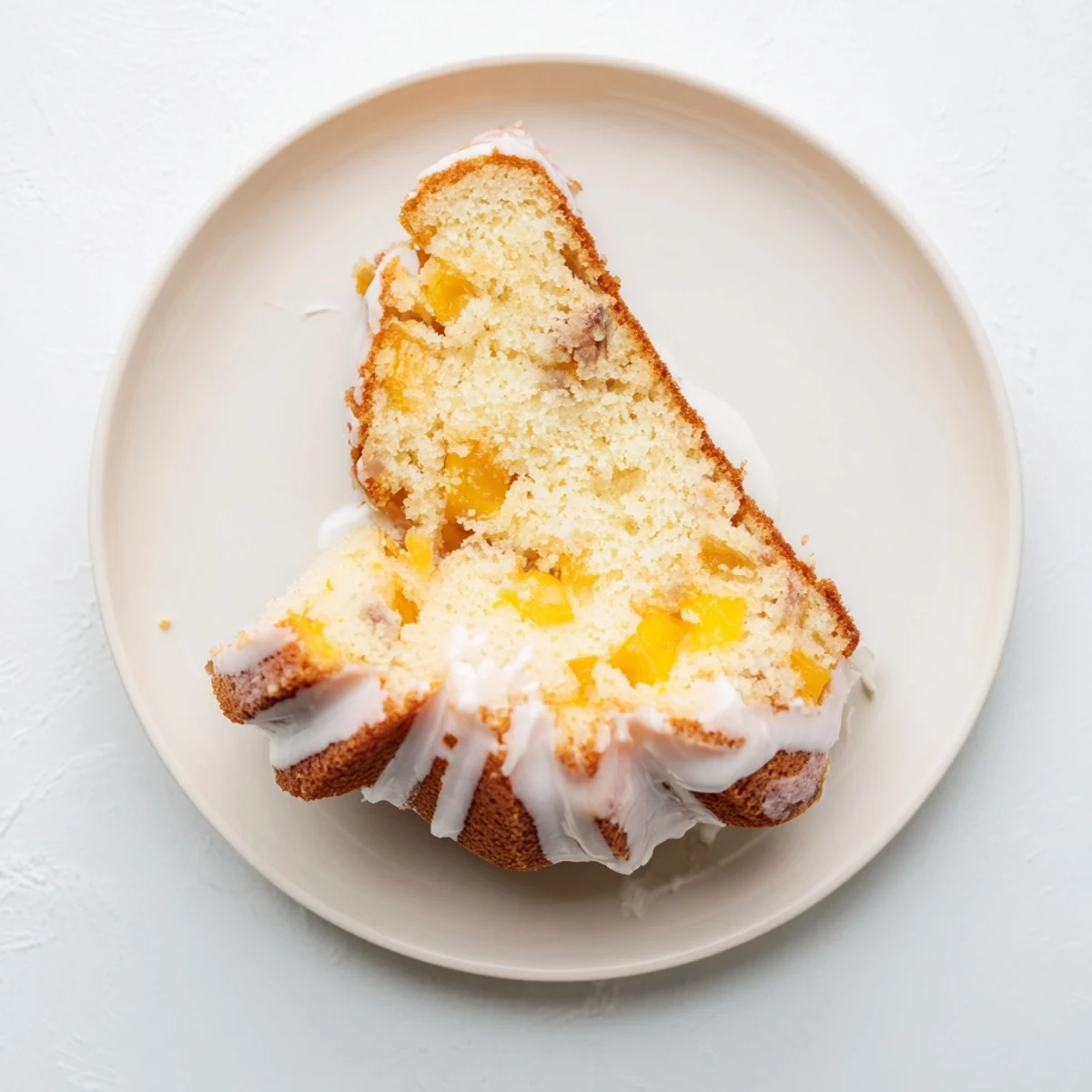 Decadent peach cobbler pound cake served on white plate with whipped cream topping