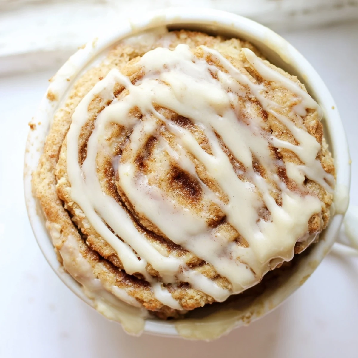 Warm high protein cottage cheese cinnamon roll mug cake with sweet cinnamon swirl and cream cheese icing drizzle
