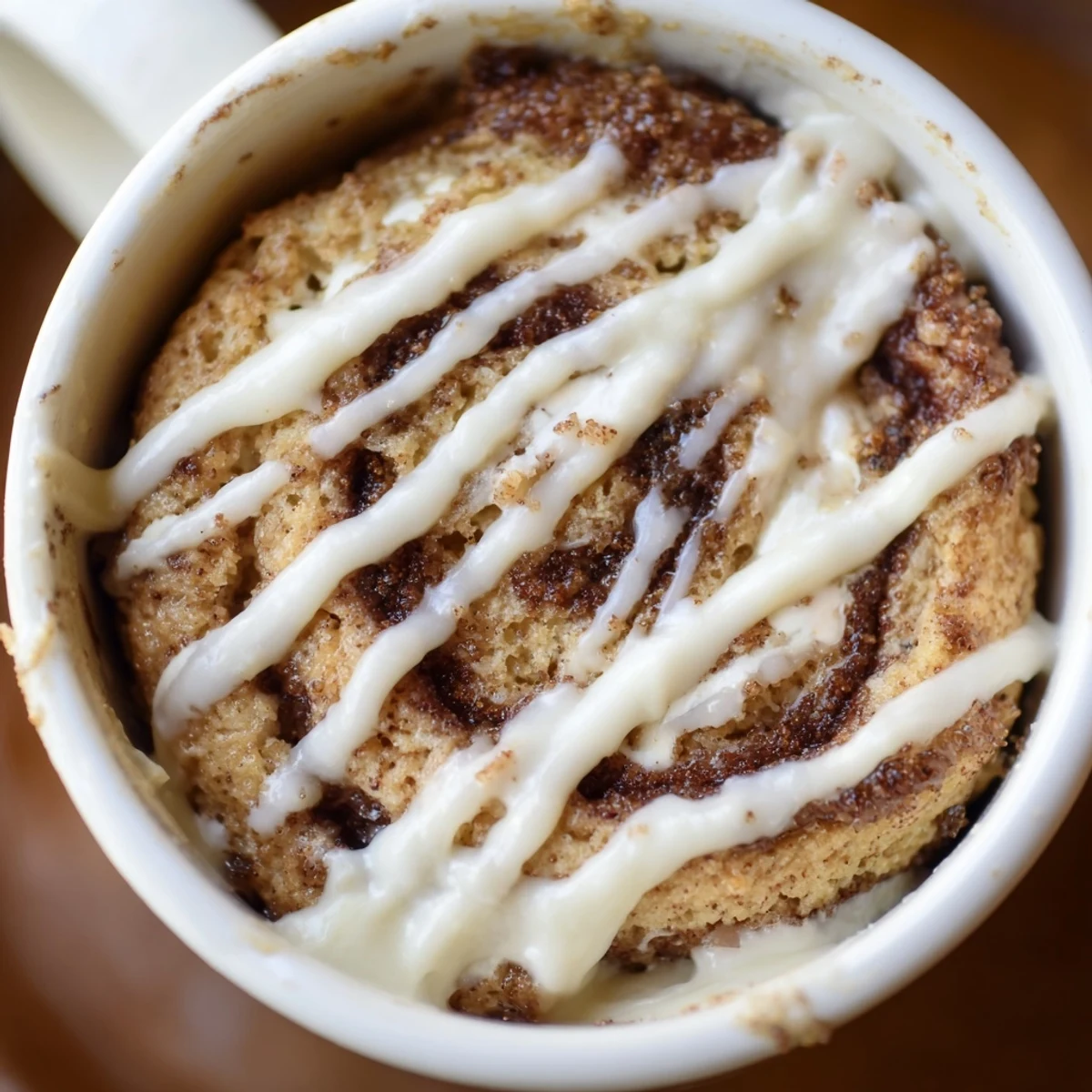 Protein-packed cottage cheese mug cake featuring ribbons of brown sugar cinnamon and vanilla cream cheese frosting