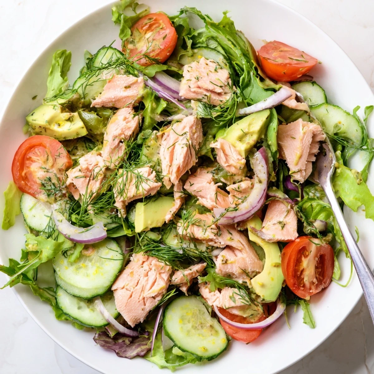 Golden pan-seared salmon chunks arranged on colorful bed of arugula and vegetables