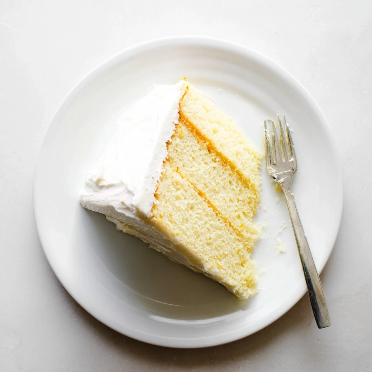 Homemade church cake with fluffy white frosting and a slice removed showing tender vanilla crumb