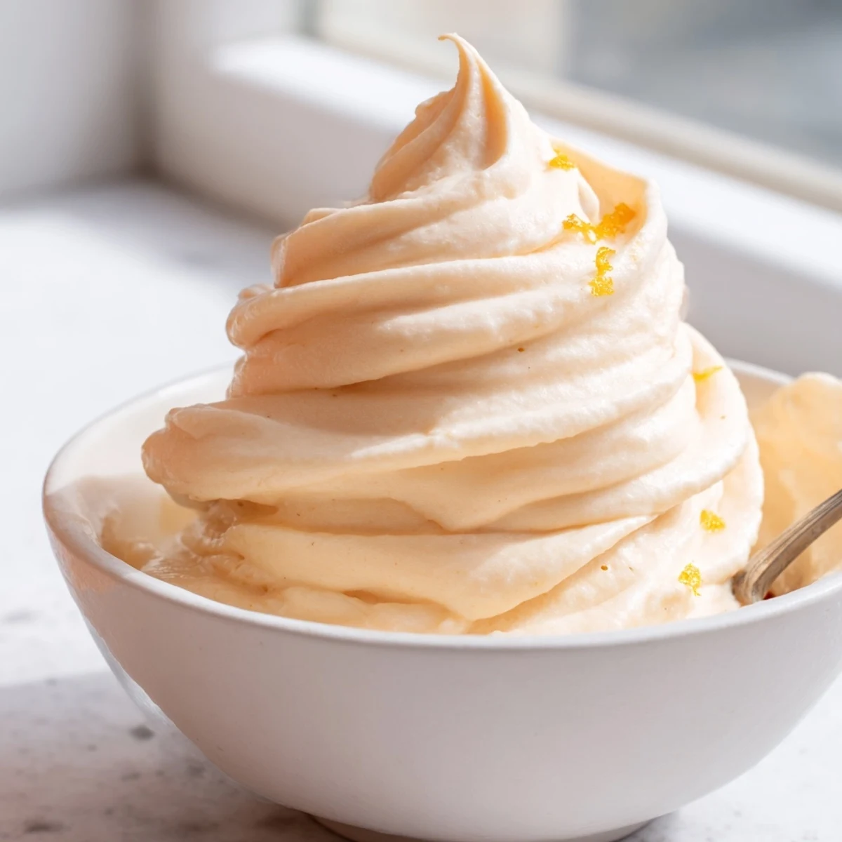 Refreshing frozen homemade orange Dole Whip served in a tall glass with pineapple chunks