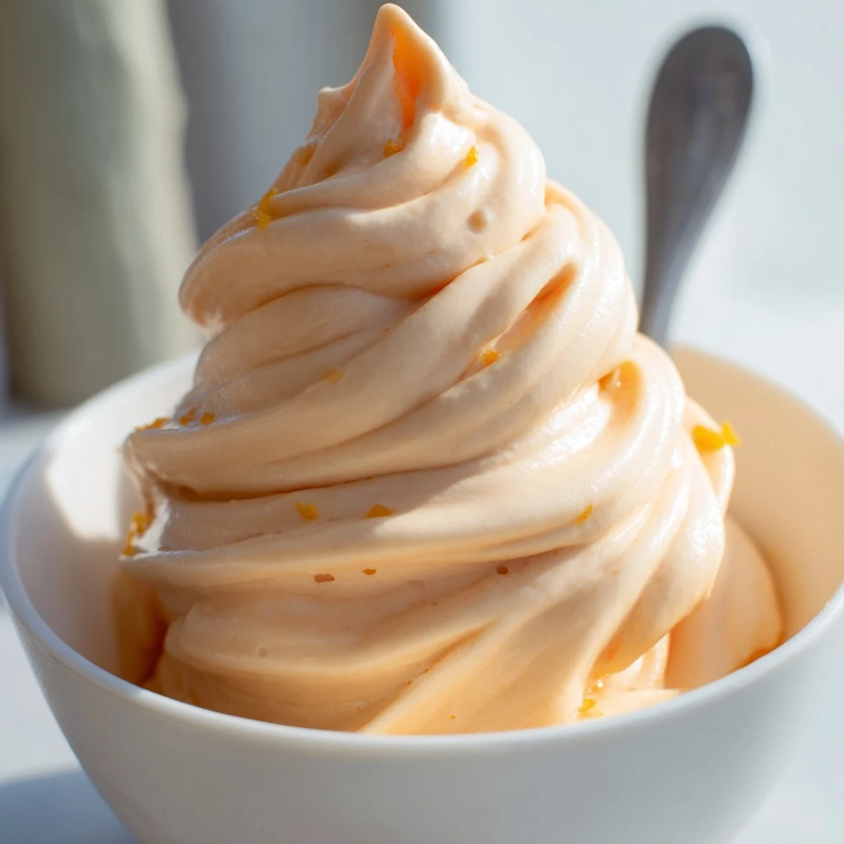 Creamy homemade orange Dole Whip swirled in a bowl with fresh orange zest garnish