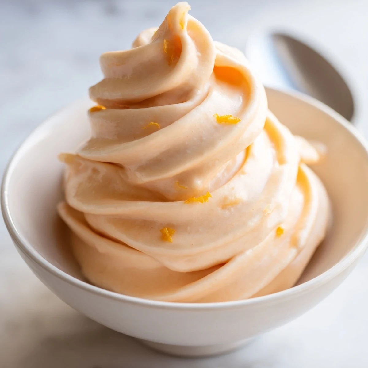 Smooth and bright homemade orange Dole Whip topped with zest and fresh orange slice