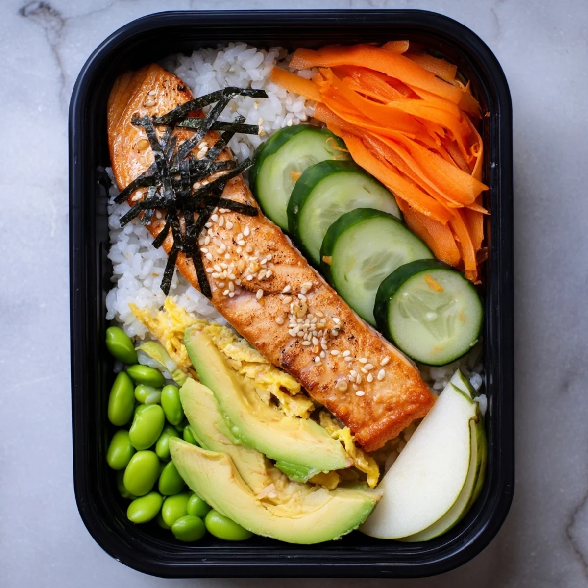 Healthy Japanese breakfast bento box featuring grilled salmon with steamed rice and colorful pickled vegetables arranged in compartments