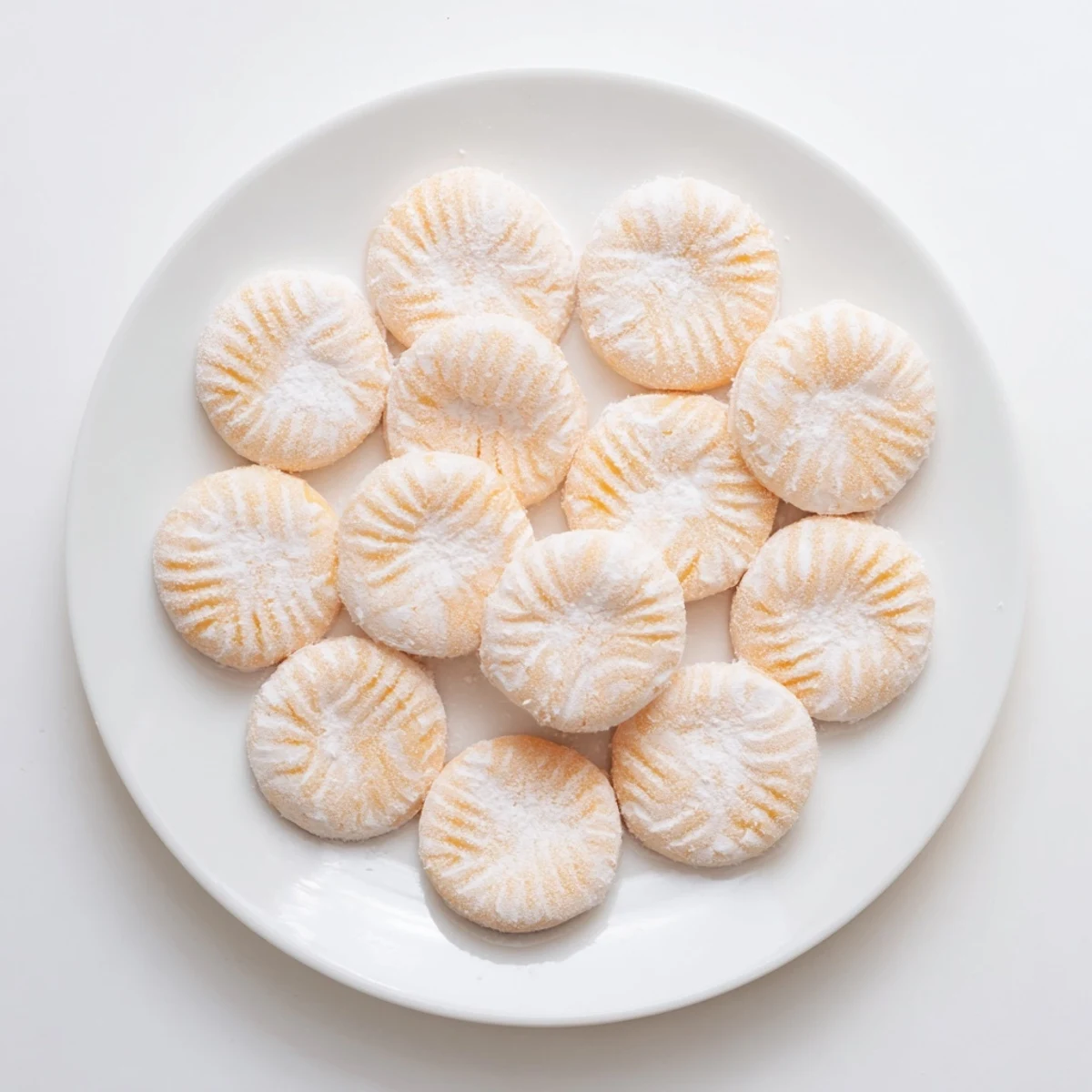 Creamy orange mints with fork impressions sitting on parchment paper, ready for gifting
