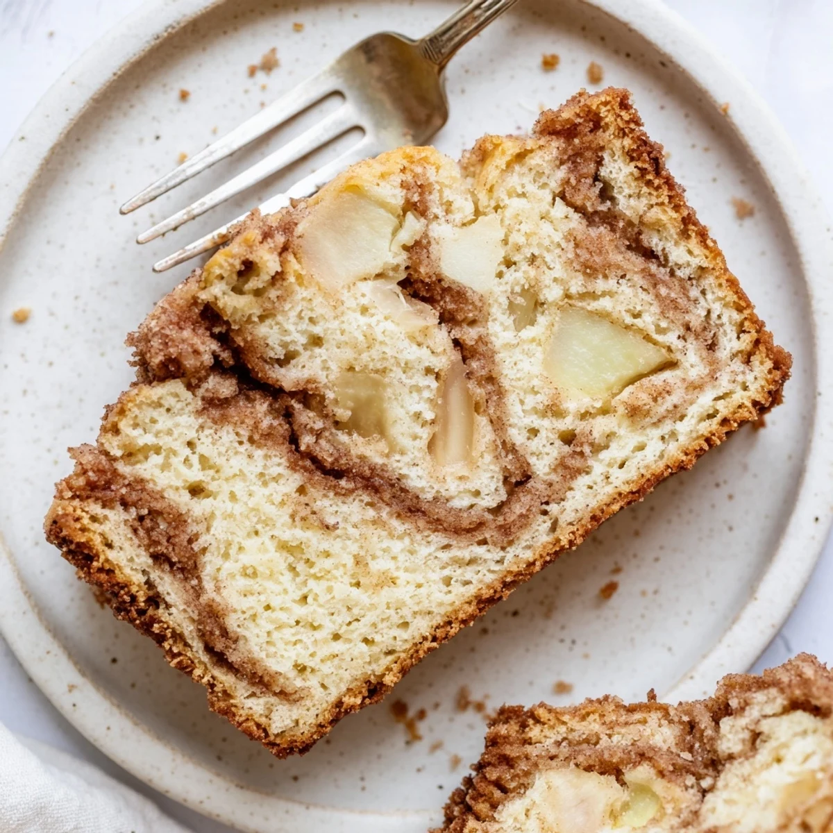 Warm slice of moist cinnamon apple bread revealing tender apple chunks and cinnamon swirl inside