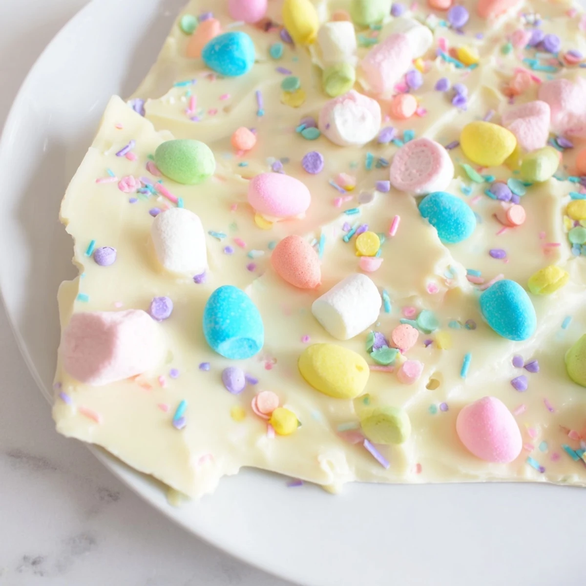 Creamy Easter marshmallow bark topped with colorful pastel candy eggs and sprinkles
