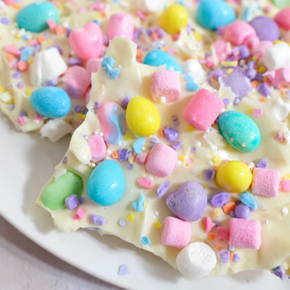 Homemade Easter marshmallow bark featuring melted white chocolate and vibrant candy toppings