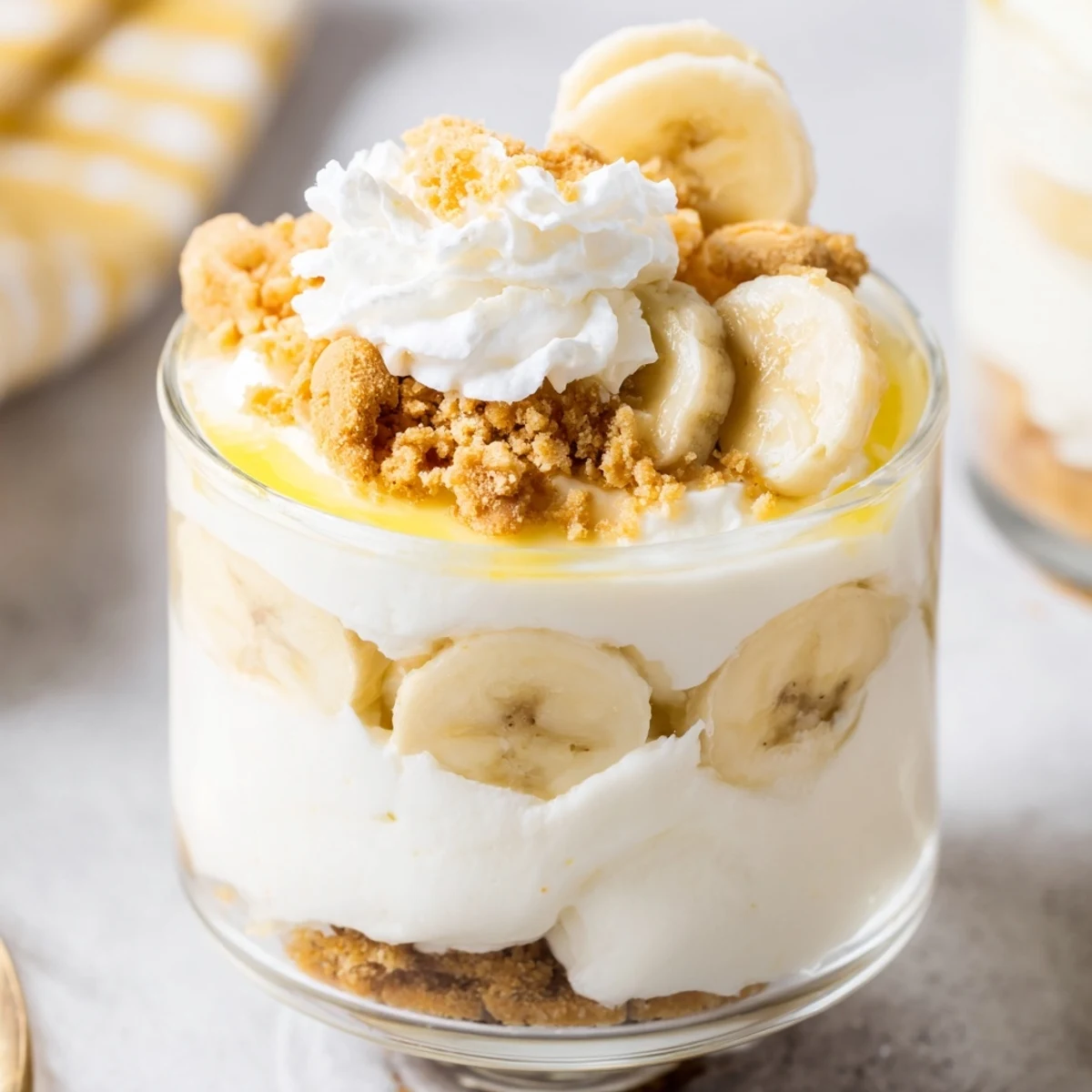 Creamy No Bake Banana Pudding Cheesecake Cups topped with fresh banana slices and vanilla wafer crumbs