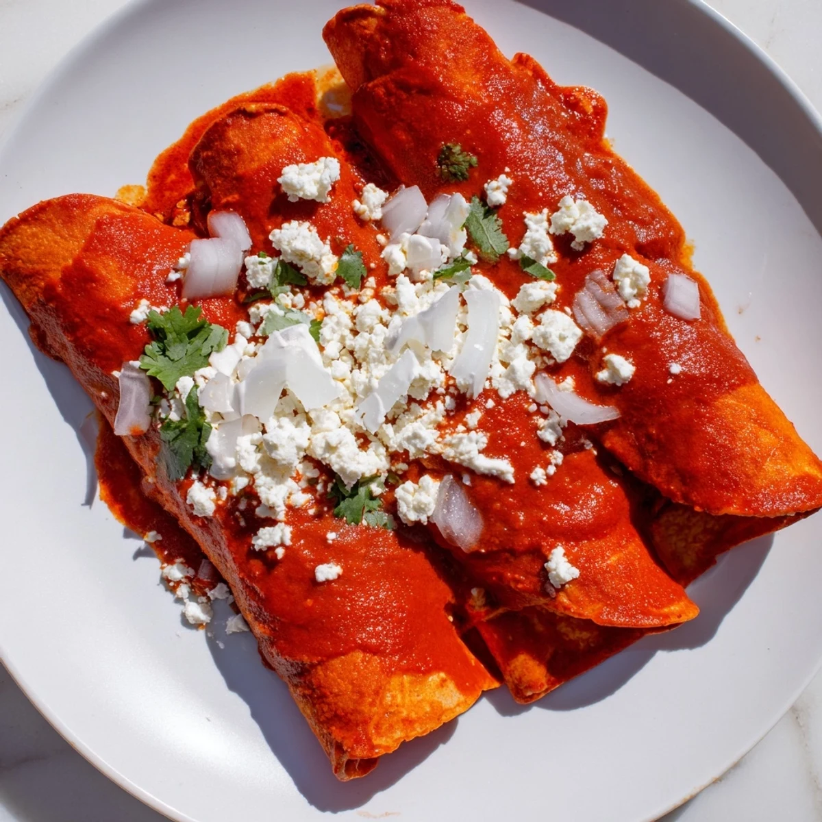 Golden entomatadas drizzled with creamy Mexican crema and sprinkled with crumbled queso fresco
