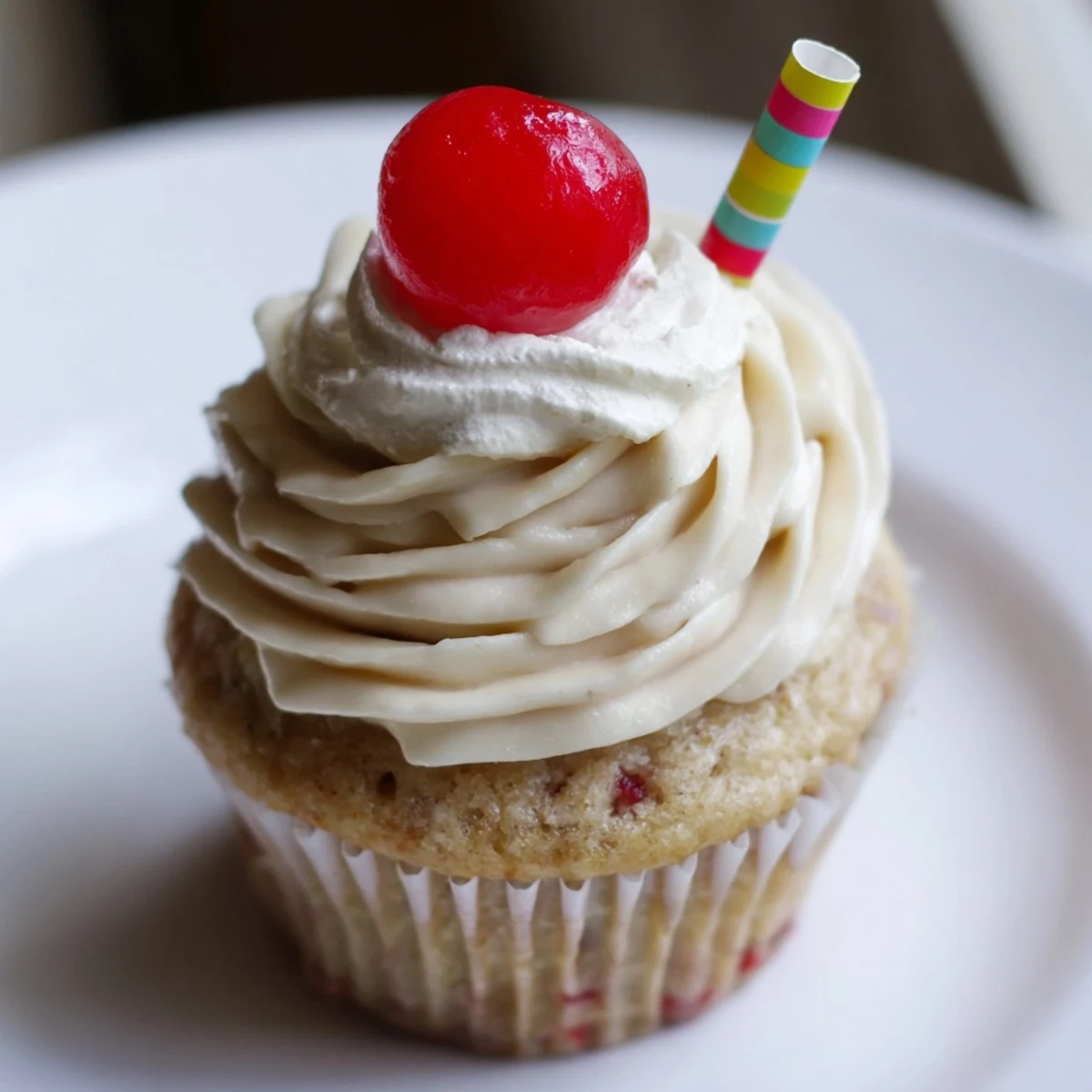 Moist banana milkshake cupcakes topped with creamy frosting and garnished with bright red maraschino cherries