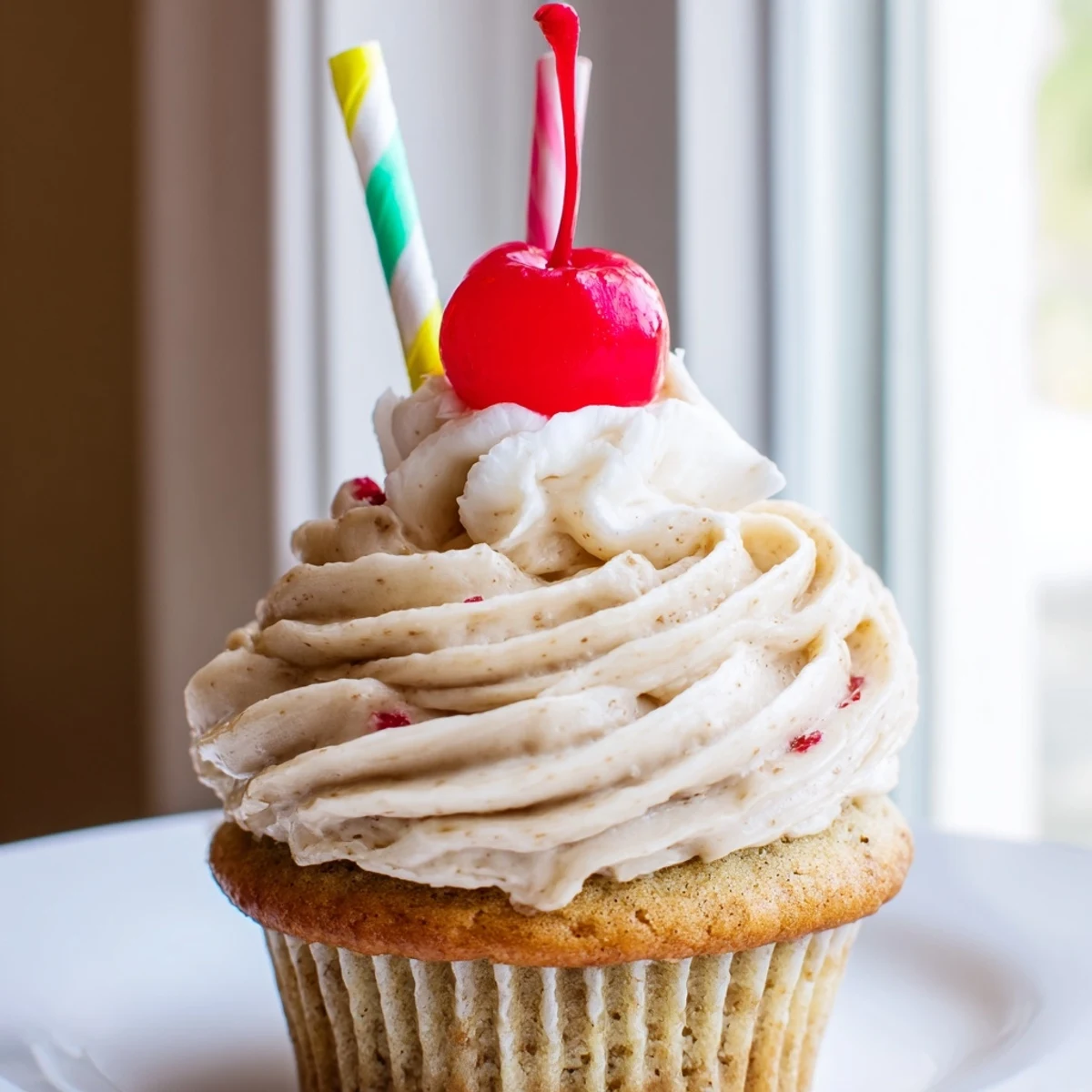 Fresh banana milkshake cupcakes with fluffy vanilla frosting served on a rustic white ceramic plate