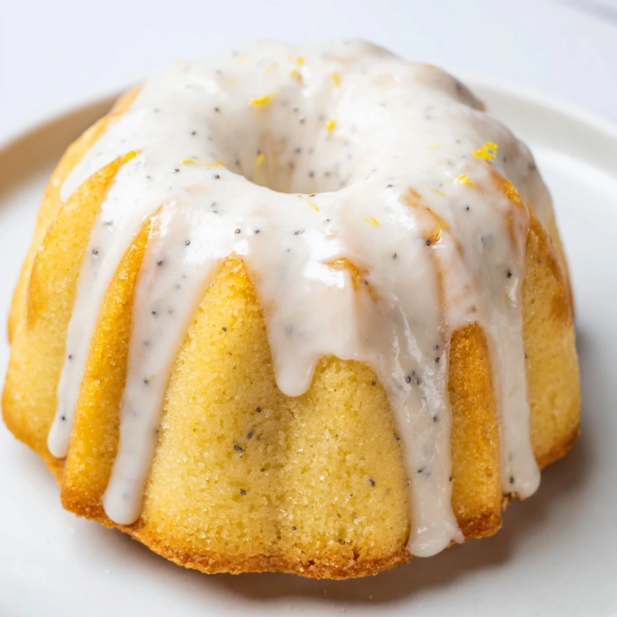 Golden mini lemon cakes drizzled with tangy glaze on a rustic white serving plate