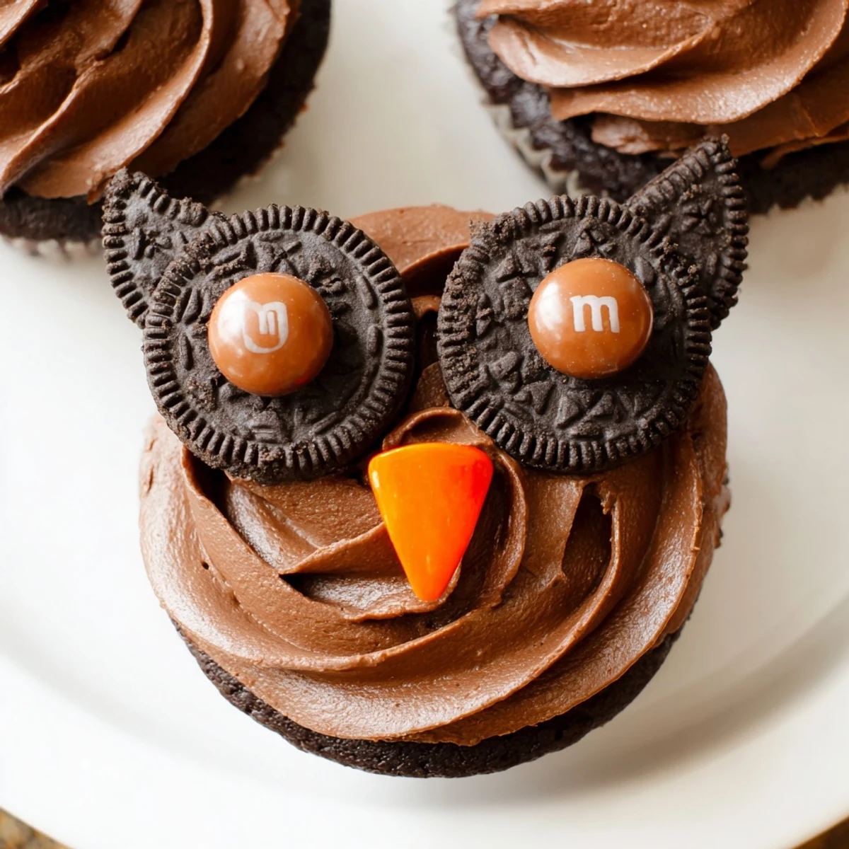 Cute Oreo Owl Cupcakes featuring twisted cookie eyes, orange candy beaks, and fluffy cocoa frosting