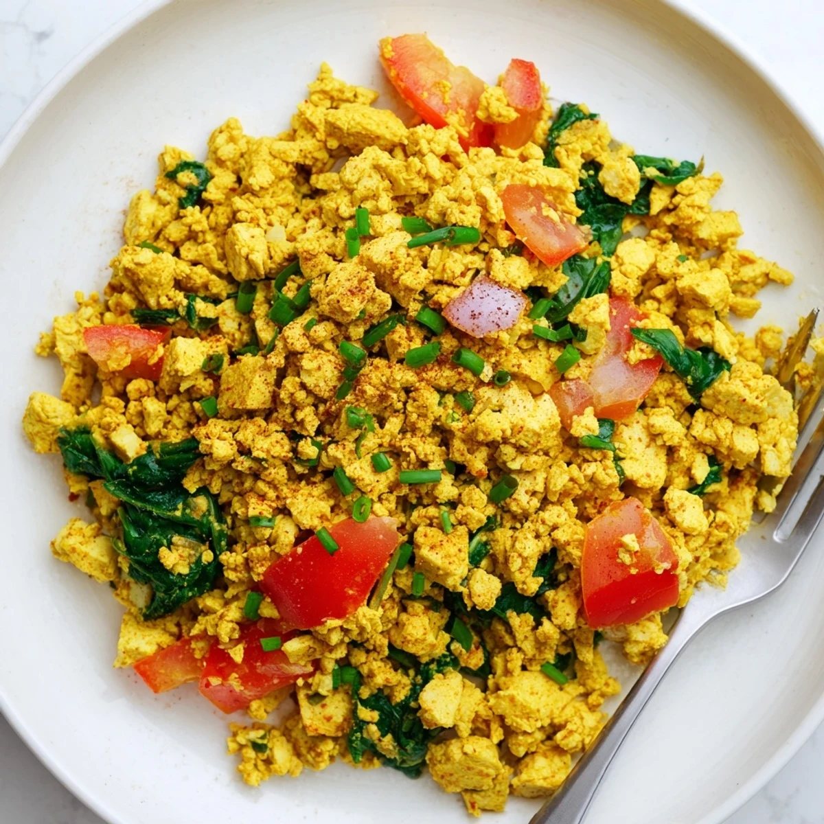 Golden turmeric Tofu Scramble topped with fresh chives, paired with toast