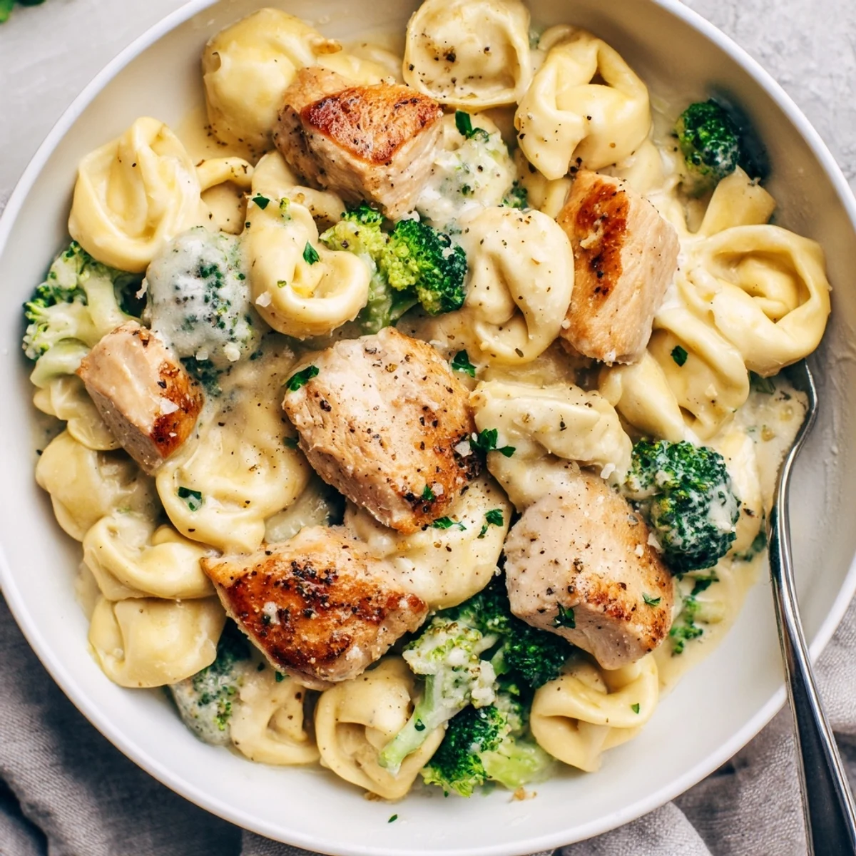 Creamy Garlic Parmesan Tortellini Chicken Broccoli Recipe showing golden chicken, steaming cream sauce